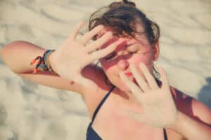 Woman holding up her hands to block the sun from damaging her face.